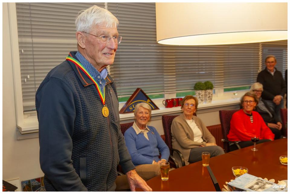 Piet Arends met een Medaille van Verdienste in een ruimte met drie andere genodigden.