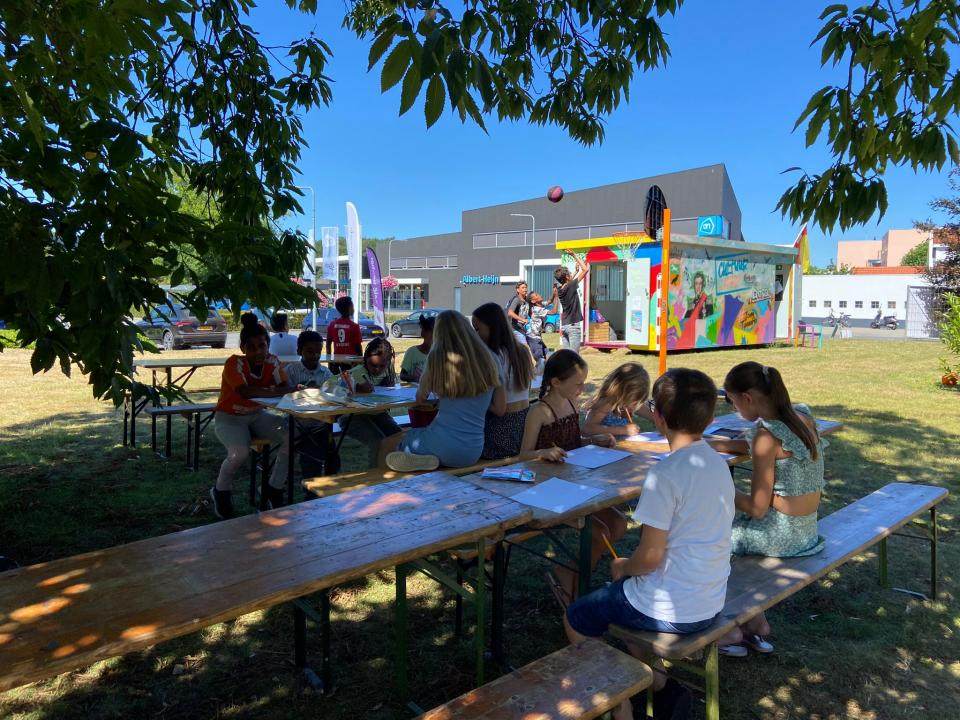 een groep kinderen buiten aan het tekenen en spelen met een bal