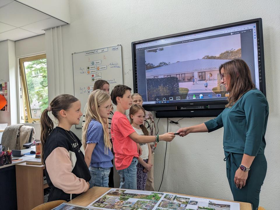 Leerlingen van de basisschool overhandigen een usb-stick aan de wethouder