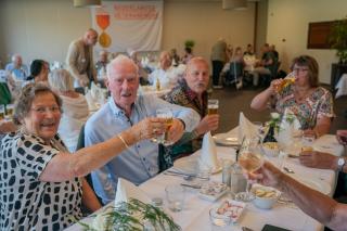 6 mensen proosten met elkaar aan tafel