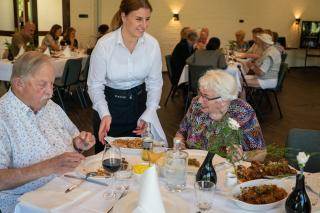 Serveerster serveert Indische maaltijd uit aan mensen aan tafel