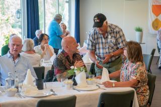 Veteranen in gesprek met elkaar, twee zitten aan tafel en de ander staat tussen de twee veteranen in.