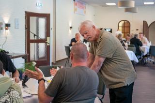 Veteranen in gesprek, de een zit en de ander staat