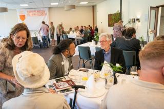 Wethouder Miguel Ririhena in gesprek met veteraan aan tafel